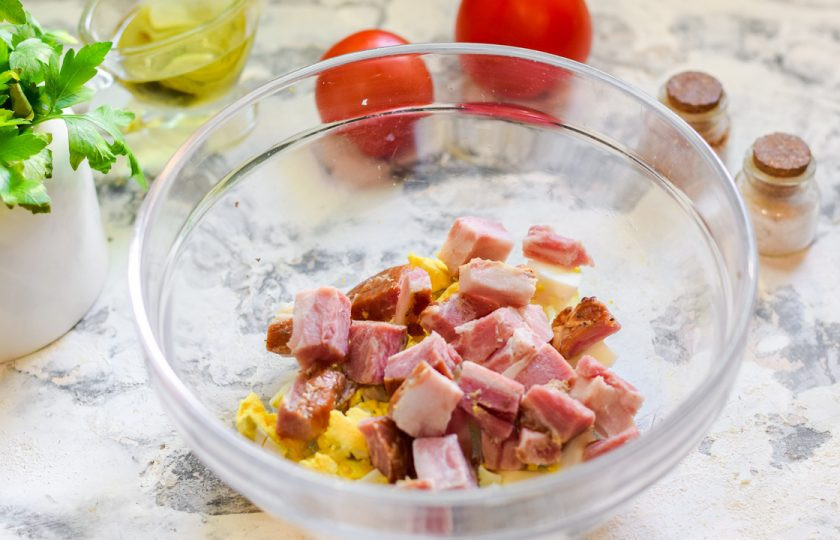 1. Этап. Салат Красная шапочка с помидорами: Мясо нарежьте небольшими кубиками и переложите к яйцам.