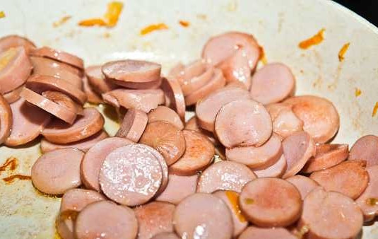 1. Этап. Вкусный фасолевый суп: 10. На сковороду добавьте еще немного масла и выложите нарезанные кружочками сосиски. На сильном огне обжарьте их до образования аппетитной корочки.