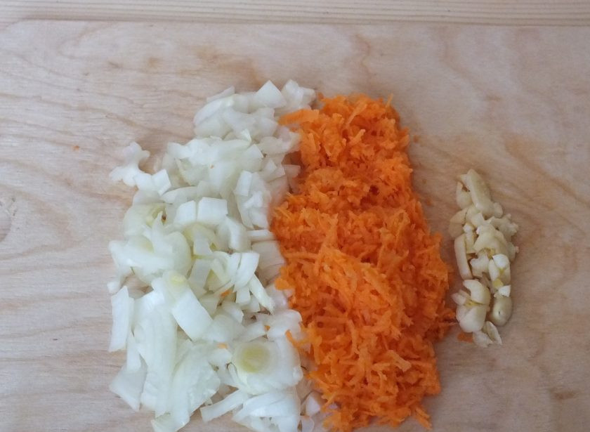 1. Этап. Профитроли с курицей: Во время выпечки сделайте начинку. Нарежьте помельче лук, натрите морковь, измельчите чеснок. Обжарьте или потушите овощи в небольшом количестве воды до готовности.