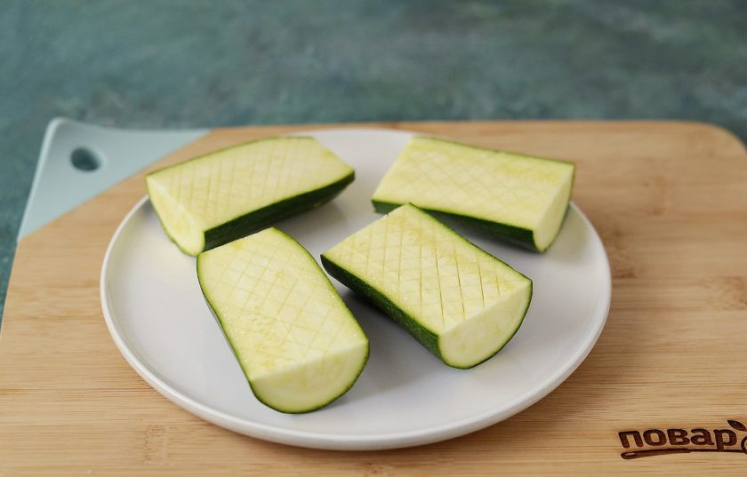 1. Этап. Кабачки с паприкой в духовке: Кабачок разрежьте на 3-4 части, затем каждую вдоль. Сделайте на ломтиках неглубокие надрезы крест-накрест.