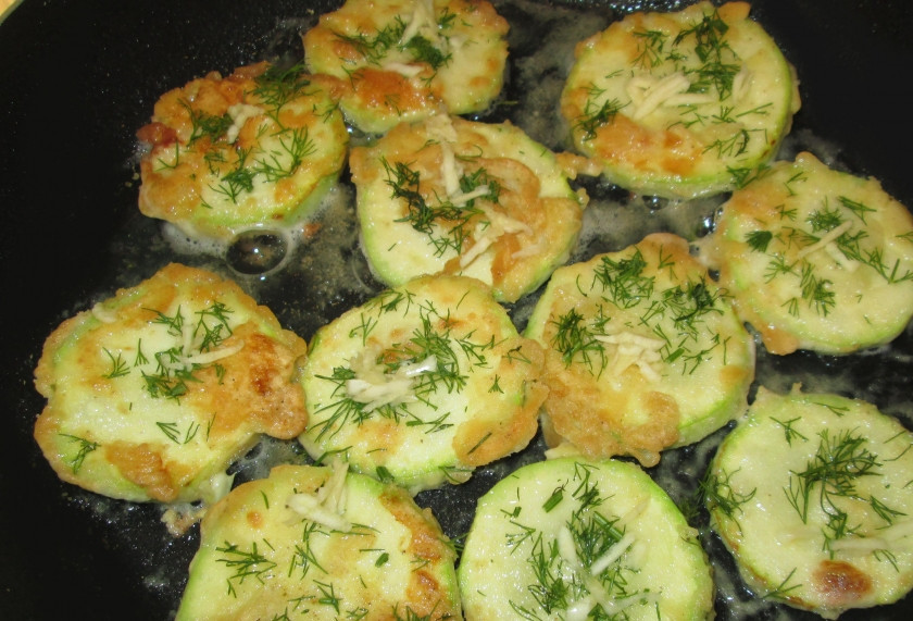1. Этап. Кабачки на сковороде: На разогретой сковороде в масле обжариваем кабачки. Перевернув, посыпаем зеленью и измельченным чесноком.