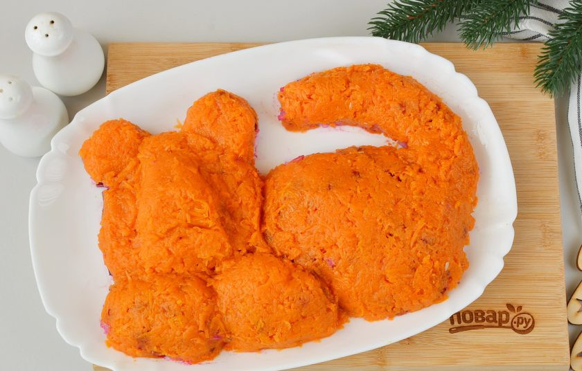 1. Этап. Салат Тигр в шубе на Новый год: Морковь натрите на самой мелкой терке, если она очень сочная, то отожмите немного. Сделайте тонкий морковный слой.