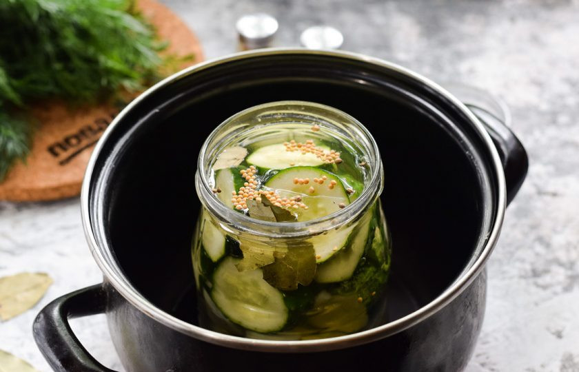 1. Этап. Огурчики по-болгарски на зиму: Дно кастрюли устелите тканью, поставьте банку, прикройте крышкой, залейте теплой водой, доведите до кипения. Стерилизуйте огурцы 15 минут.