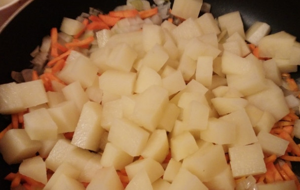 1. Этап. Тушеная картошка с капустой: 3. Очистите картофель от кожуры. Нарежьте небольшими кусочками. Добавьте картофель к овощам на сковороде. Поставьте овощи на средний огонь. Готовьте под крышкой. Периодически овощи перемешивайте.