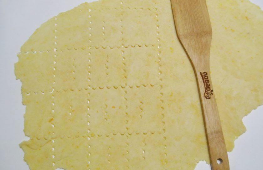 1. Этап. Итальянский хворост: Раскатайте тесто толщиной 2-3 мм на столе, посыпанном мукой. Нарежьте на квадраты или прямоугольники. В центре сделайте разрез.