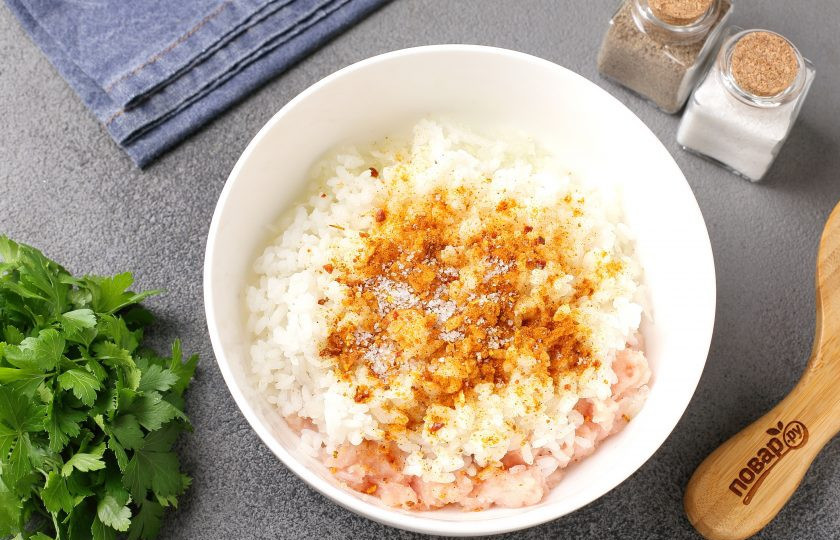 1. Этап. Куриные тефтели в духовке в сливочно-сырном соусе: Рис отварите до полуготовности, промойте и добавьте к фаршу. Добавьте сюда же тёртый на крупной тёрке лук, соль и специи по вкусу.