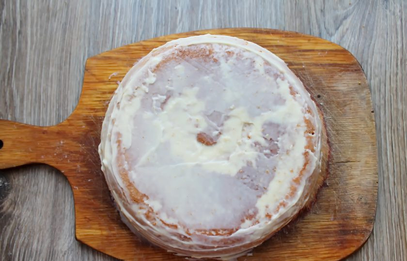 1. Этап. Торт Чародейка в мультиварке: Выложите верхний корж и немного прижмите. Обмажьте поверхность торта оставшимся кремом тонким слоем.