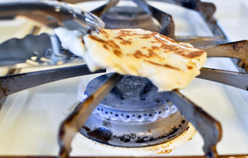 1. Этап. Домашние лепешки наан: 7. Теперь готовить наан с другой стороны наан над пламенем газовой горелки, держа их щипцами. Когда вы увидите обугленные коричневые пятна, наан готовы.