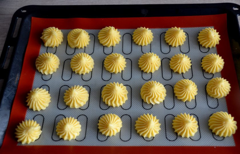 1. Этап. Профитроли с масляным кремом: Переложите тесто в кондитерский мешок и отсадите на лист для выпечки на расстоянии друг от друга.