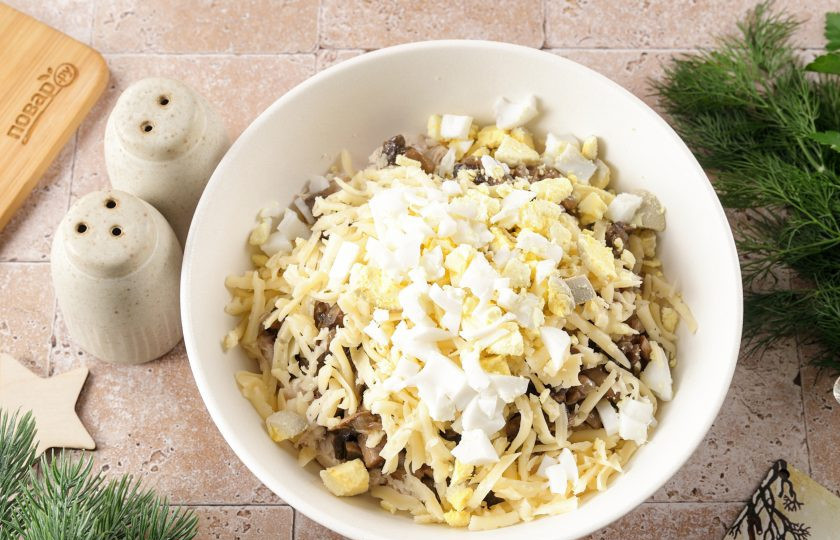 1. Этап. Новогодний салат Варежка на год Змеи: Яйца очистите и нарежьте кубиками. Два белка и один желток оставьте для украшения. Сыр натрите на крупной тёрке.