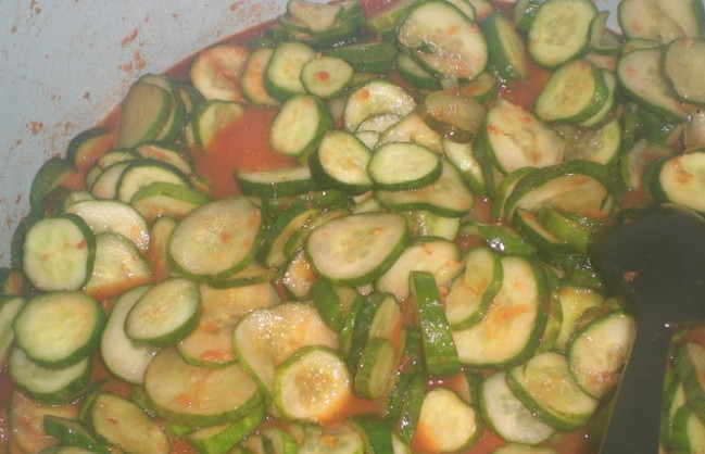 1. Этап. Огурцы в томатной заливке: 3. Пропускаем через мясорубку томаты с острым перцем, насыпаем соль, сахар, подсолнечное масло, отправляем на огонь и тушим после закипания 7-10 минут. После этого кладем огурцы и тушим еще 10-15 минут. За несколько минут до окончания приготовления добавляем уксус и чеснок.