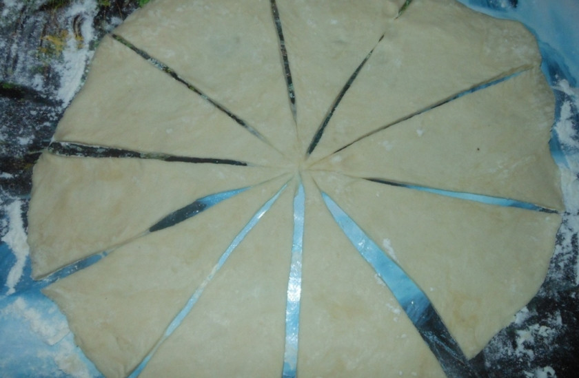 1. Этап. Постные рогалики: Тесто обомните и разделите на 3 части, каждую раскатайте в пласт, каждый из которых затем разрежьте на треугольники.