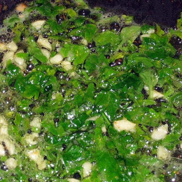 1. Этап. Ризотто с красной рыбой: В сковороде разогреваем сливочное масло. Обжариваем в масле небольшие кусочки чеснока (каждый зубчик надо разрезать на 5-6 кусочков), спустя 2 минуты добавляем нарубленную зелень. Обжариваем 1 минуту на среднем огне, активно перемешивая.