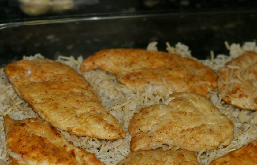 1. Этап. Запеканка с курицей, рисом и грибами: 1. Сперва разрежьте грудки вдоль на 2 части. Посыпьте солью, перцем и мукой, обжарьте на раскаленной сковороде. В форму для выпечки выложите отварной рис, затем уложите кусочки грудки.