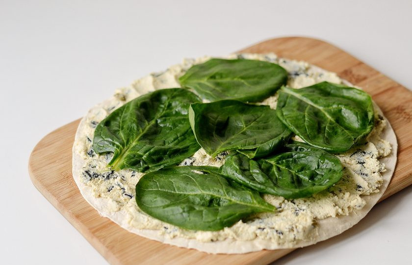 1. Этап. Постные начинки для лаваша: Нанесите начинку равномерным слоем на лаваш. Сверху выложите листья шпината. Скрутите рулет, заверните его в фольгу и уберите на пару часов в холодильник настояться.