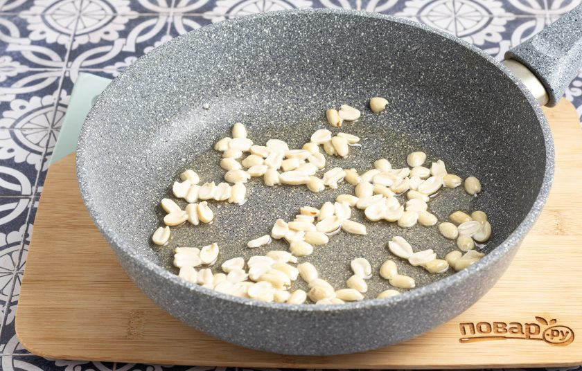 1. Этап. Фасоль с арахисом: Разогрейте сковороду с растительным маслом. Добавьте крупно порубленный арахис и жарьте около 2-3 минут до слегка золотистого цвета.