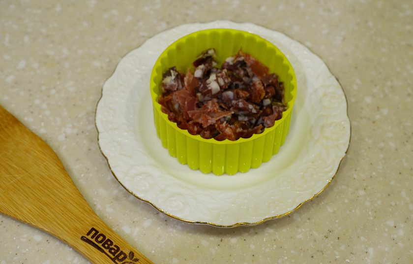 1. Этап. Слоеный салат с кукурузой: 2. На тарелку поставьте формовочное кольцо и выложите первым слоем колбасу, затем немного майонеза.