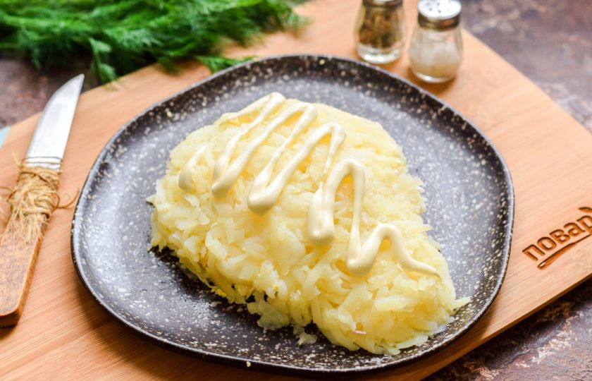 1. Этап. Слоеный салат с курицей Бычок: Картофель натрите на средней терке. Выложите картофель поверх салата, также немного опуститесь вниз, как показано на фото — создавая силуэт головы бычка.