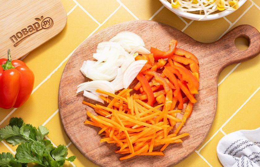 1. Этап. Салат из пророщенной сои по-корейски: Подготовьте овощи. Репчатый лук нарежьте перьями, болгарский перец соломкой, а морковь очистите от кожуры и натрите на терке для моркови по-корейски.