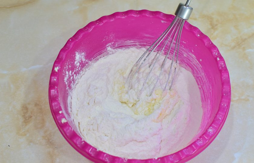 1. Этап. Итальянское печенье из сливочного сыра: Постепенно подсыпайте муку с содой и вмешивайте её в тесто.