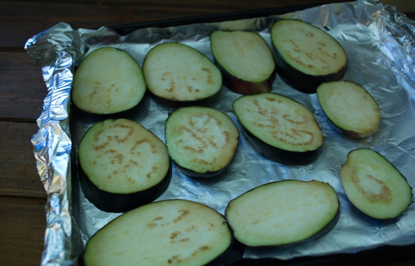 1. Этап. Баклажаны, запеченные с помидорами и сыром: Противень застелите фольгой. Фольгу смазать маслом. Выложить сырые баклажаны в один слой.