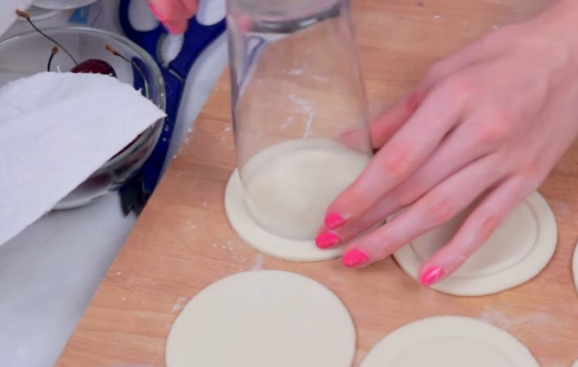 1. Этап. Слоеные пирожки на завтрак: 1. Слоеное тесто извлеките из упаковки и слегка раскатайте скалкой. Затем вырежьте круги стаканом, это будут наши пирожки. На каждом круге с помощью стакана чуть поменьше диаметром выдавите еще один круг.