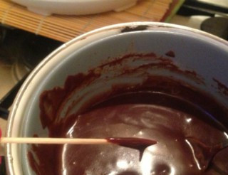 1. Этап. Пирожные на палочке: Растопим на водяной бане шоколад. Можно в разных мисочках растопить белый и темный. Достаем из морозилки шарики-пирожные. Деревянную шпажку окунаем в шоколад и втыкаем в шарик.