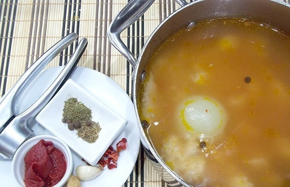 1. Этап. Классический суп Харчо: Продолжайте варить харчо на небольшом огне. Добавьте в него пропущенный через пресс чеснок, томатную пасту, измельчённый острый перец, кориандр и хмели-сунели.