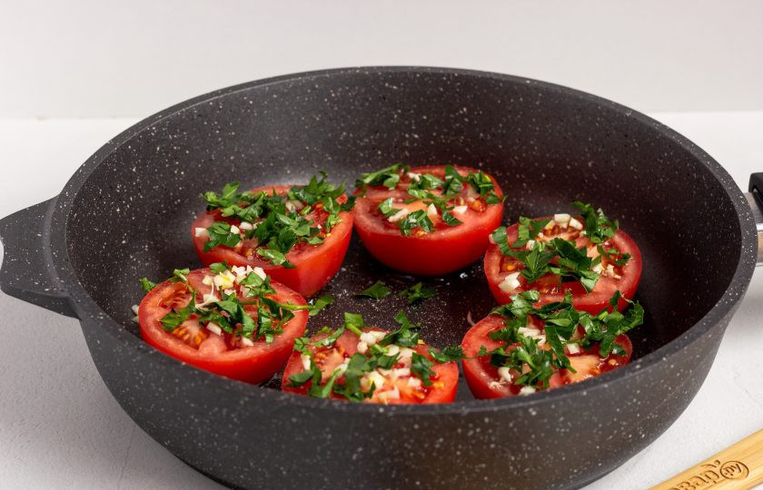 1. Этап. Помидоры по-гречески: Присыпьте помидоры сахаром, посолите по вкусу. Затем добавьте рубленную зелень и мелко рубленный чеснок.