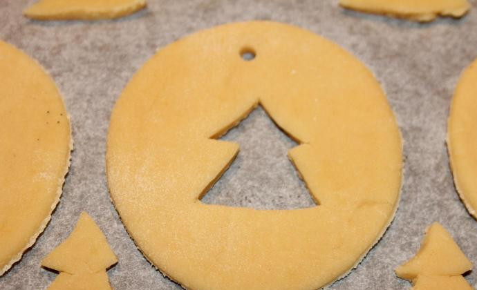 1. Этап. Новогоднее печенье на елку: Трубочкой для коктейлей сделайте небольшие дырочки. В эту дырочку потом можно будет продеть нитку и повесть печенье на елку. В центре каждого печенья с помощью ножа и круглой формочки сделайте отверстия.