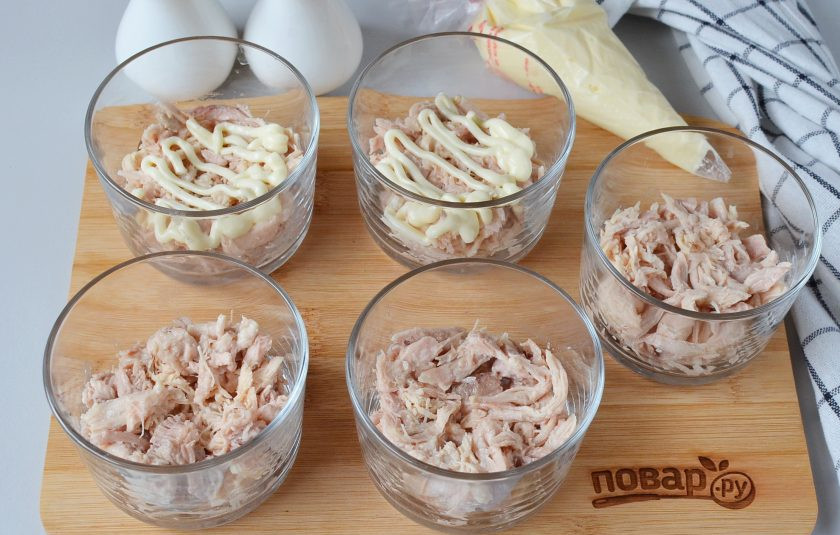 1. Этап. Новогодний слоеный салат: В пять стаканов для салата разложите вареное мясо. Смажьте тонким слоем майонеза. Соль и перец используйте по вкусу.