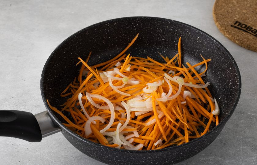 1. Этап. Салат из соленого папоротника по-корейски: Разогрейте растительное масло в сковороде. Добавьте морковь и репчатый лук. Потушите 1-2 минуты.