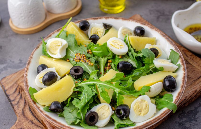 1. Этап. Салат Нисуаз с рукколой: Отварной картофель очистите и нарежьте на дольки, яйца очистите и разрежьте пополам. Выложите на 