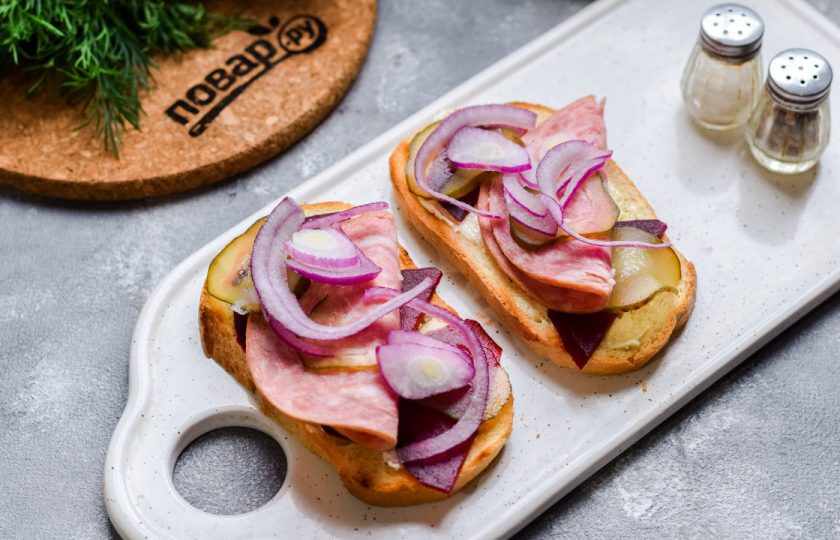 1. Этап. Датские бутерброды: Добавьте соленый огурец нарезанный пластинами, также добавьте немного красного лука, нарезанного полукольцами или кубиками.