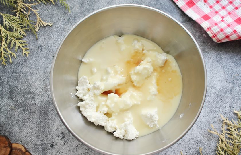 1. Этап. Ленивый кекс с персиками и творогом: В миску протрите творог, добавьте сгущенку и ванильный экстракт. Пробейте все до однородности блендером.