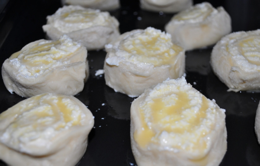 1. Этап. Завитушки с творогом в сметанной заливке: Получившиеся творожные кусочки раскладываем на противне, который предварительно нужно смазать маслом. Раскладываем так, чтобы между будущими завитушками оставалось пространство. Сверху смазываем взбитым яйцом. Оставляем пока будущие булочки на 40 минут. А затем ставим их в разогретую до 180-200 градусов духовку и выпекаем до румяности.