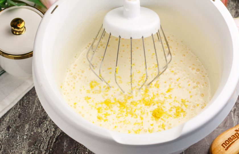 1. Этап. Бисквитный пирог с лимоном: Ошпарьте лимон кипятком и вытрите насухо. Натрите цедру на терке с мелкими ячейками прямо в емкость. Выжмите сок из половины лимона, если он мелкий, и из четверти, если плод крупный. Всыпьте пшеничную муку по частям и тщательно перемешайте.