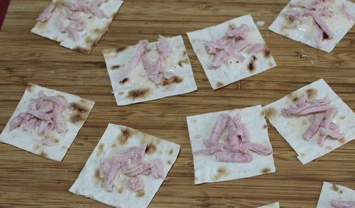 1. Этап. Закуска Хрустяшки: Лаваш разрезать на квадратики. В середину выложить немного сметаны. Посыпать сосисками.