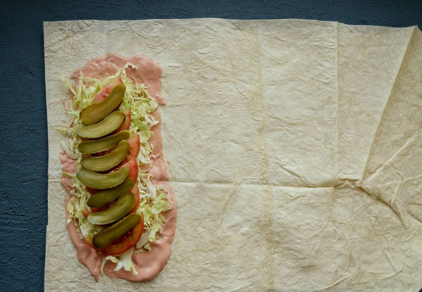 1. Этап. Постная шаурма: Сверху выложите капусту. На неё положите огурчики и дольки помидора.