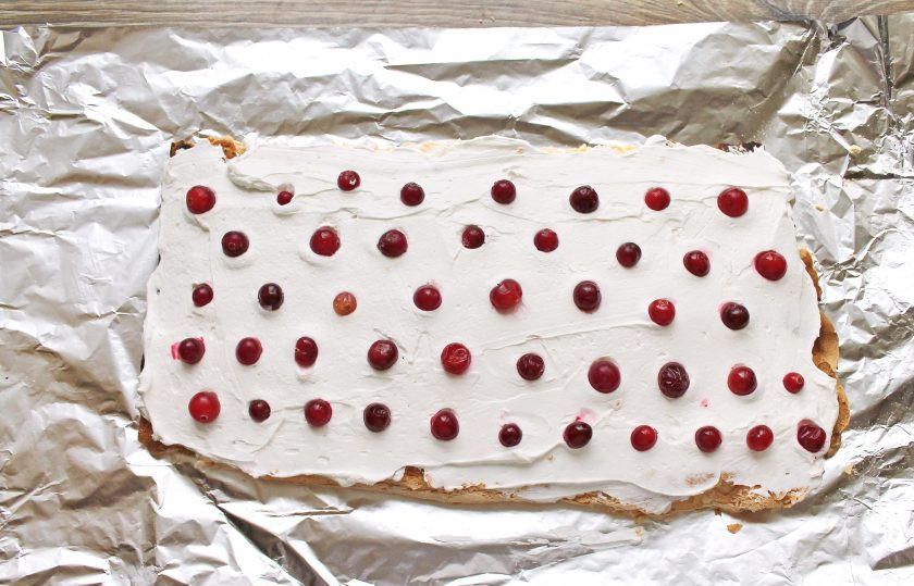 1. Этап. Меренговый рулет с клюквой: Положите крем на меренговый пласт, и разложите ягоды клюквы в шахматном порядке рядами.