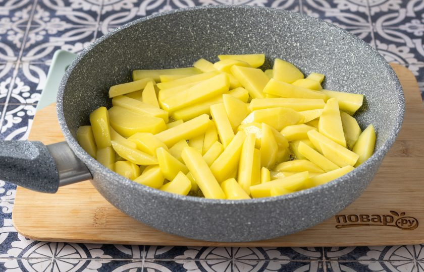 1. Этап. Жареная картошка на оливковом масле: Хорошо разогрейте сковороду с оливковым маслом. Выложите в кипящее масло подготовленный картофель. Перемешайте так, чтобы все брусочки покрылись оливковым маслом. Жарьте на средне-высоком огне, пока нижняя сторона не станет румяной.