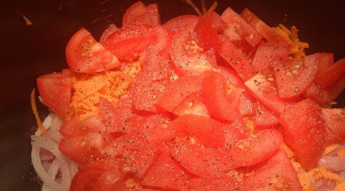 1. Этап. Грудка индейки в мультиварке Редмонд: Помидор нарежьте кольцами, которые затем разрежьте на четыре части, чтобы получились небольшие ломтики. Морковь натрите на крупной терке. Добавьте помидоры и морковь в чашу мультиварки.