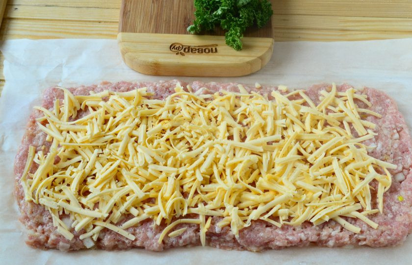 1. Этап. Сытные фрикаделины с начинкой: Твердый сыр натрите на крупной терке и выложите ровным слоем на фарш.