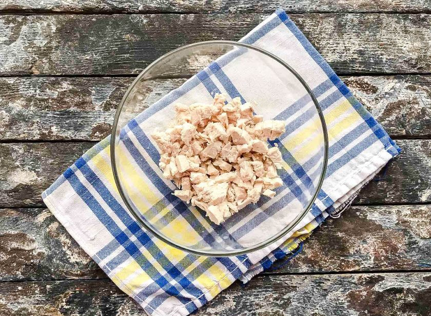 1. Этап. Салат с филе курицы: Филе курицы отварите в подсоленной воде, дайте ей полностью остыть, нарежьте небольшими кусочками и выложите в глубокую тарелку.