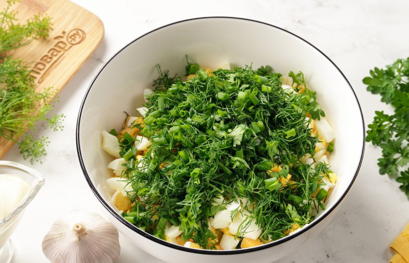 1. Этап. Салат с яйцом, сыром, кукурузой и огурцом: Добавьте рубленую свежую зелень.