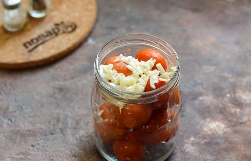 1. Этап. Помидоры Под снегом без уксуса: Чеснок очистите и натрите на крупной терке, добавьте чеснок в банки.