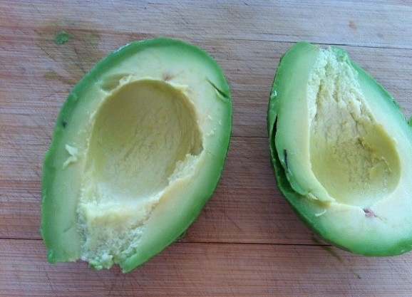1. Этап. Яйцо в авокадо с беконом: 1. Для начала авокадо разрежьте пополам. Удалите косточку. Вытащите мякоть с помощью большой ложки из кожуры.