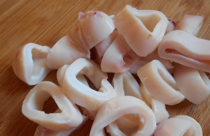 1. Этап. Кальмары постные: Кальмар почистите, удалите хитиновую пластину и промойте. Отварите тушки в подсоленном кипятке 1-2 минуты. Затем морепродукты остудите и нарежьте кольцами.