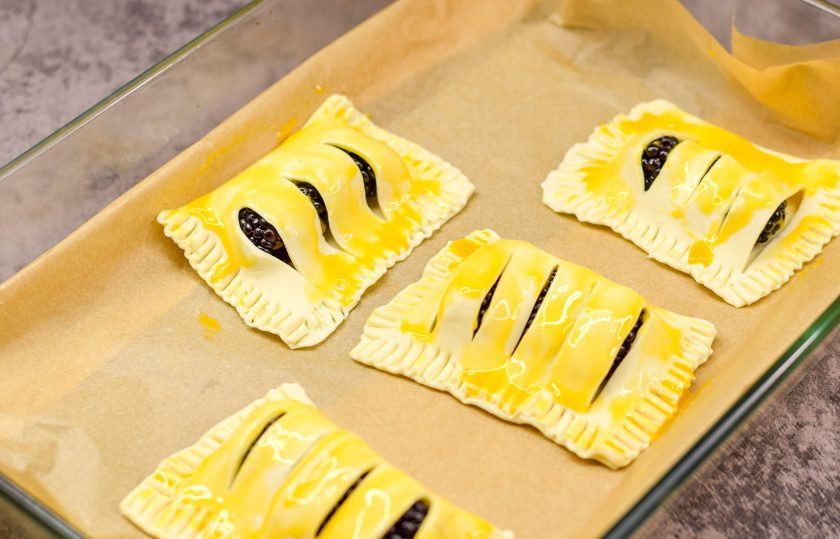 1. Этап. Слойки с ежевикой: Выложите все заготовки слоек на противень, смажьте взбитым яйцом и переставьте в духовку.