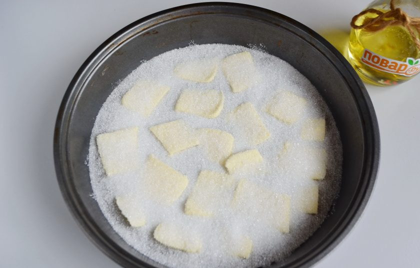 1. Этап. Яблочный пирог Татьяны Толстой: 2. Застелите дно бумагой для выпечки. Смажьте ее сливочным маслом, сверху положите ломтики холодного масла, посыпьте половиной стакана сахара.